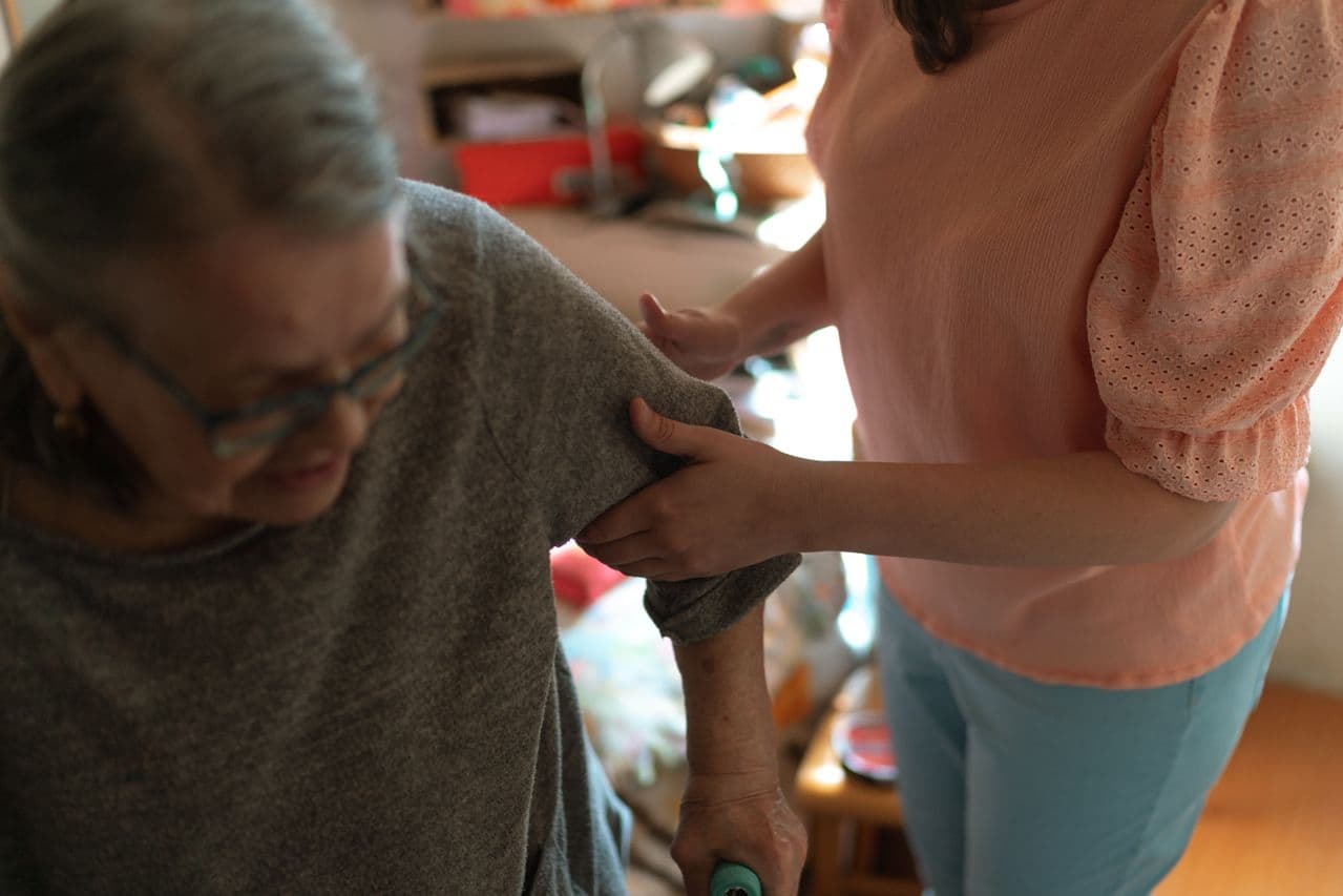 Caregiver sitting with an elderly woman at home
