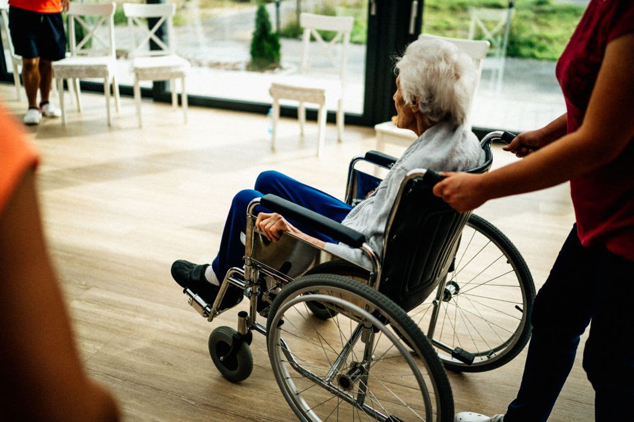 Caregiver walking with a senior using a wheelchair